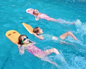 Children using swimming kickboard in pool